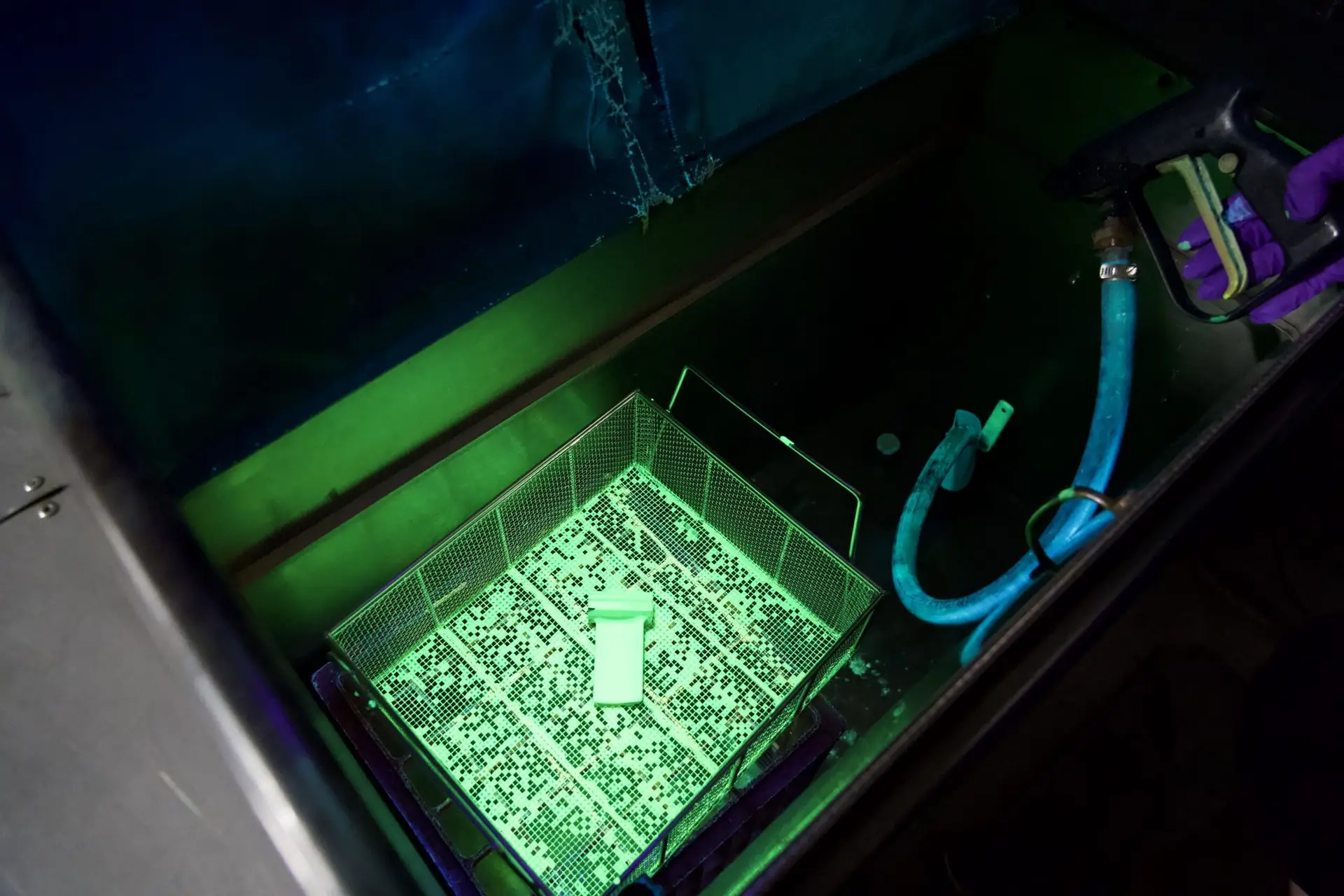 Metal component being processed during fluorescent penetrant inspection for surface defect detection.